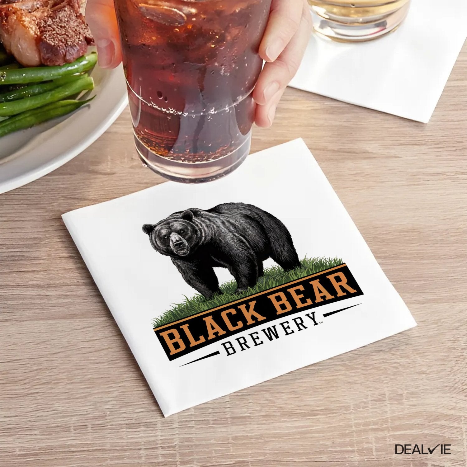 Black Bear Brewery logo on a white cocktail napkin with grass detail.