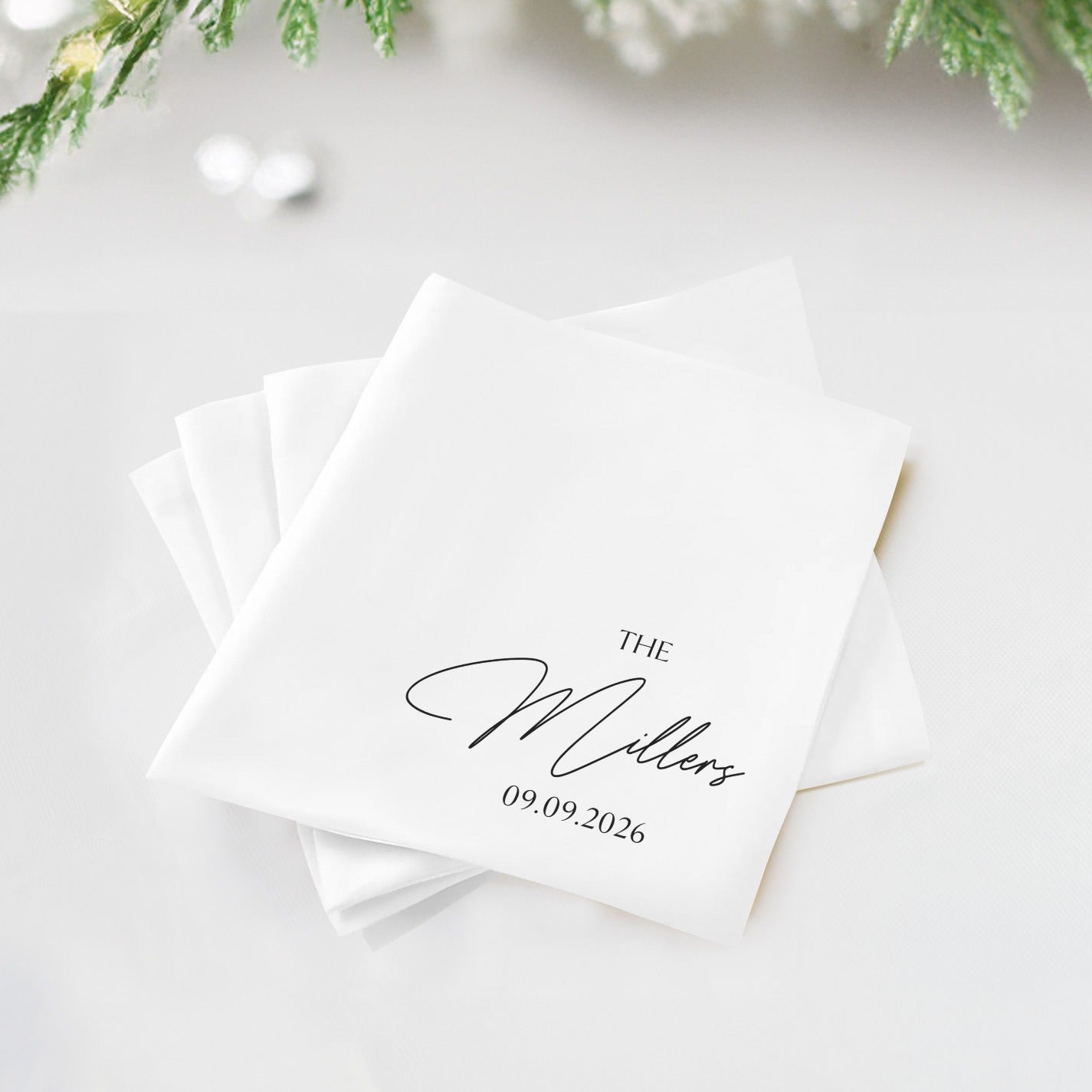 White cloth napkins with "The Millers" and "09.09.2026" printed in black script.